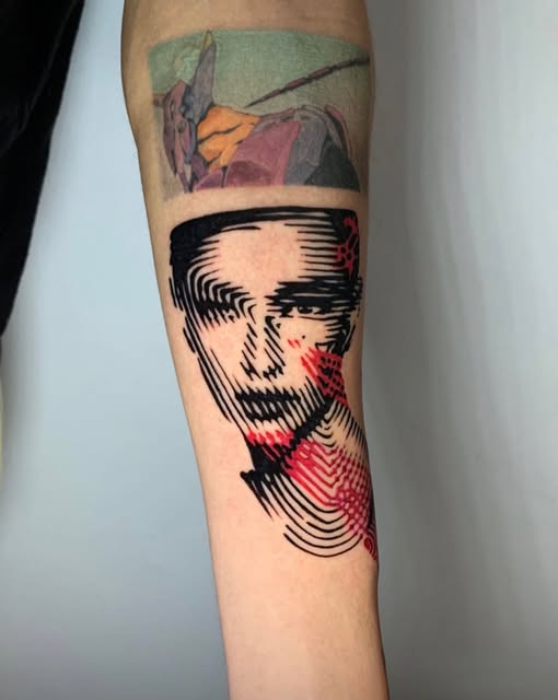 Graphic black and red portrait tattoo on an arm