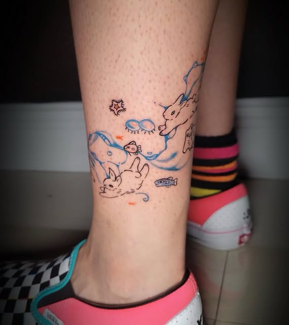 Playful blue, black and orange rabbit tattoo on a lower leg