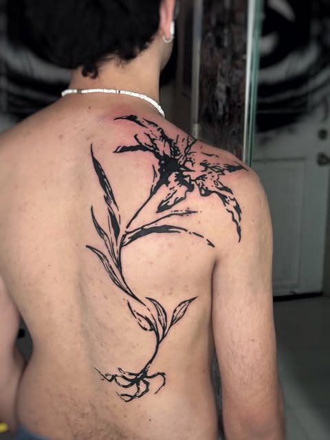 Flowing black botanical tattoo covering the upper back