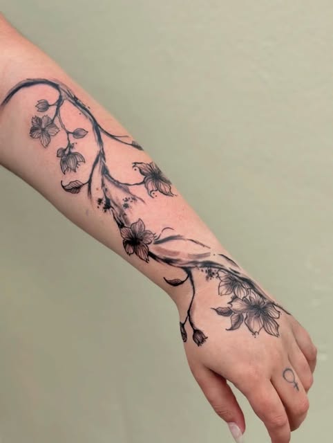 Fine-line floral tattoo extending from forearm to hand