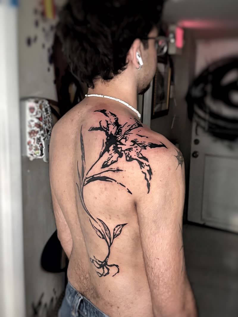 Large black floral tattoo flowing across a shoulder and upper back